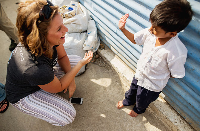 D’Anne Maddox from 1040.com gives a high five to a grinning child in a Guatemala City slum.