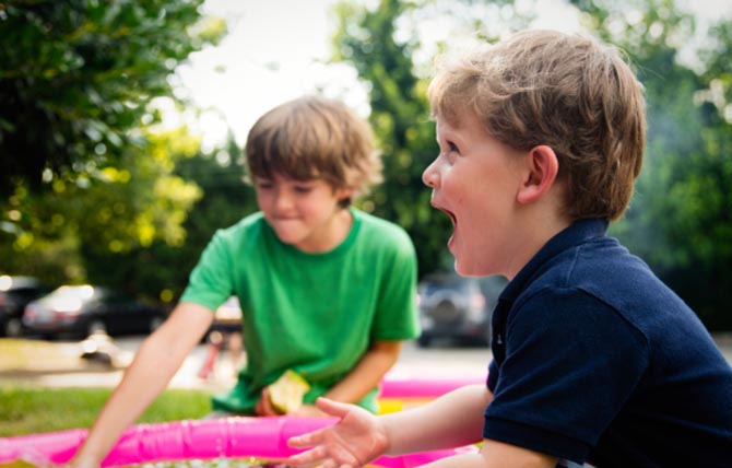 Two little boys laughing and playing outside