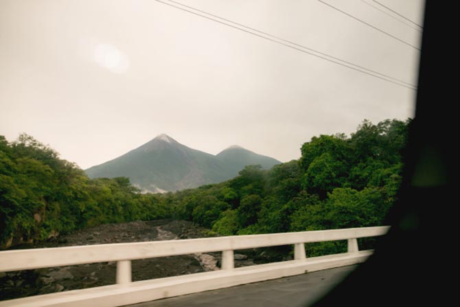 Two Guatemalan volcanos under a cloudy sky as 1040.com drives by