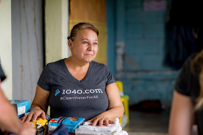 A Guatemalan feeding center owner smiles in a 1040.com shirt