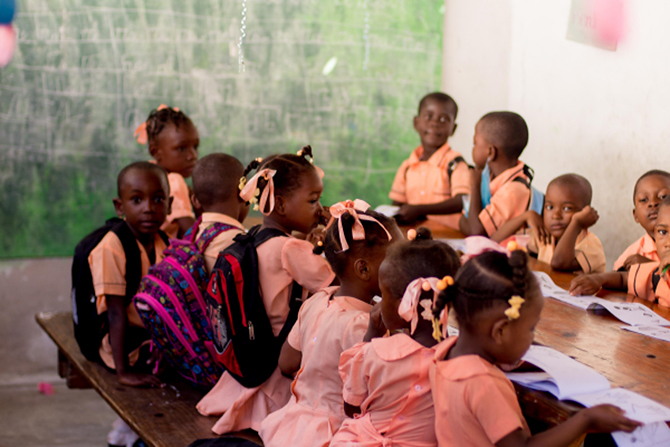 A class of Haitian children doing schoolwork by a chalkboard