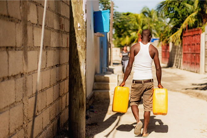 A man in Haiti carrying water back to his home