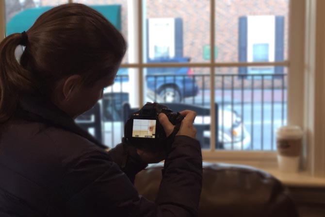 A photographer shoots a coffee cup on a window sill.