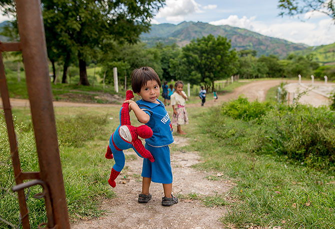 A small Guatemalan boy pauses on the road to pose with his Spiderman doll.