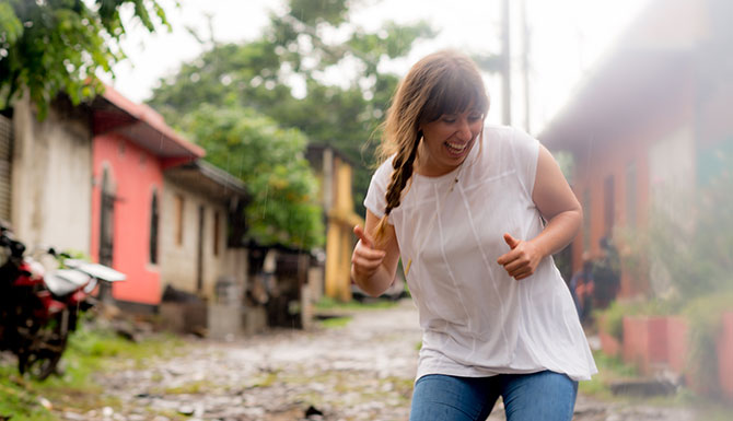 A woman laughing and dancing on a colorful street.