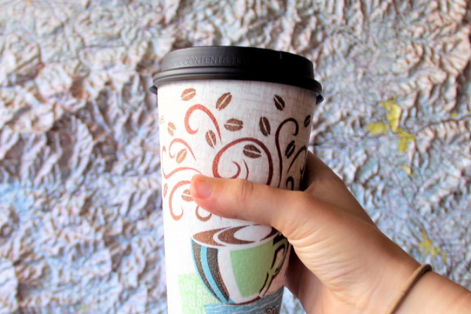 A coffee cup held in front of a map
