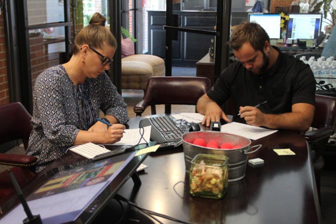 Two taxpayers fill out their Form 1040 postcards at the office.