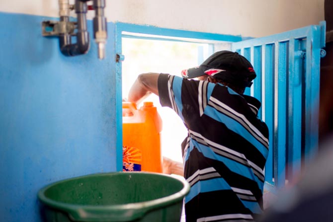 A man preparing to fill water jugs at a clean water system in Haiti