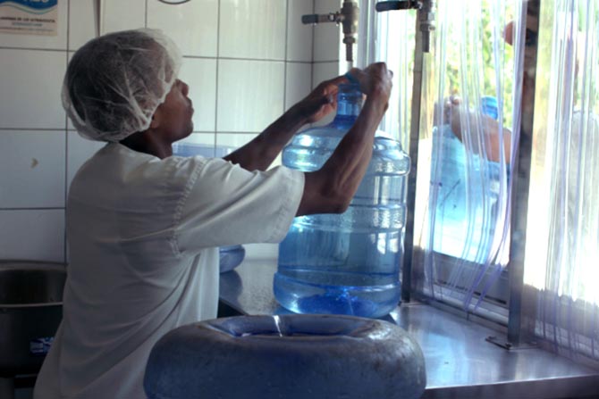 A young man sealing a five-gallon jug of clean water in a Healing Waters storefront.