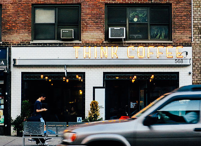 A café says “Think Coffee” by a busy street during tax season.