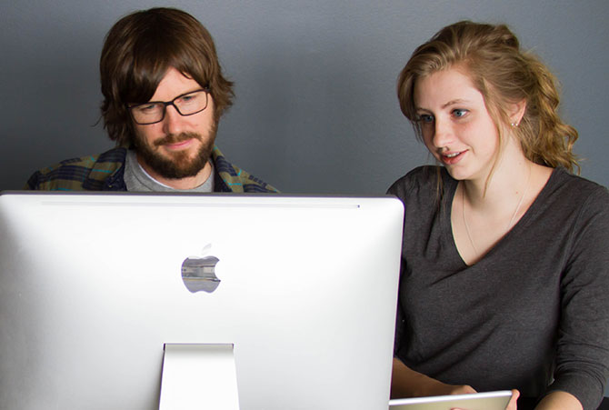 A man and a woman file their taxes on a computer.]