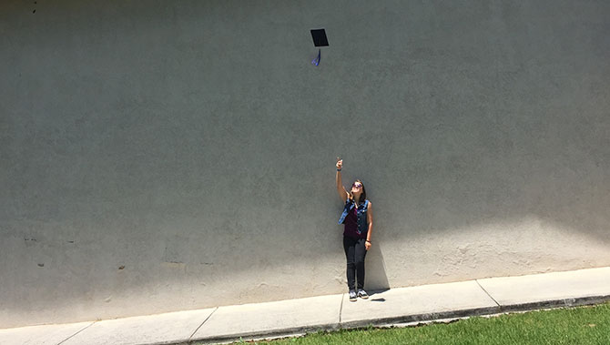 A girl throws her graduation cap into the air.