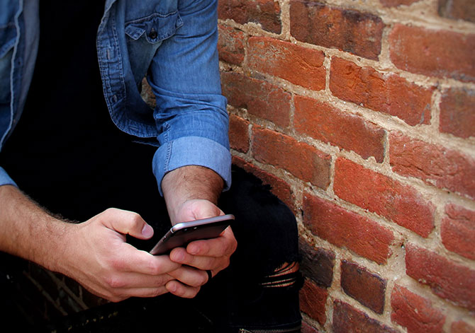 Man checks his phone on the  steps outside his apartment.]