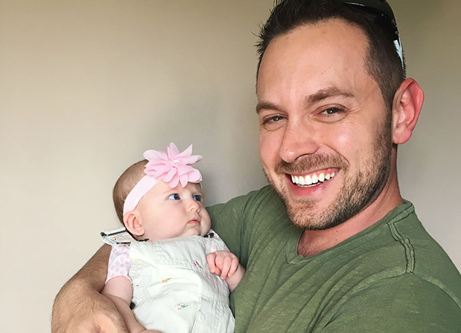  A baby girl looks suspiciously at her laughing dad.
