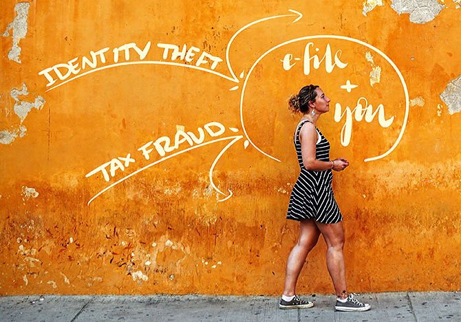 A woman walking next to an orange wall, protected from identity theft and tax fraud by e-filing her taxes