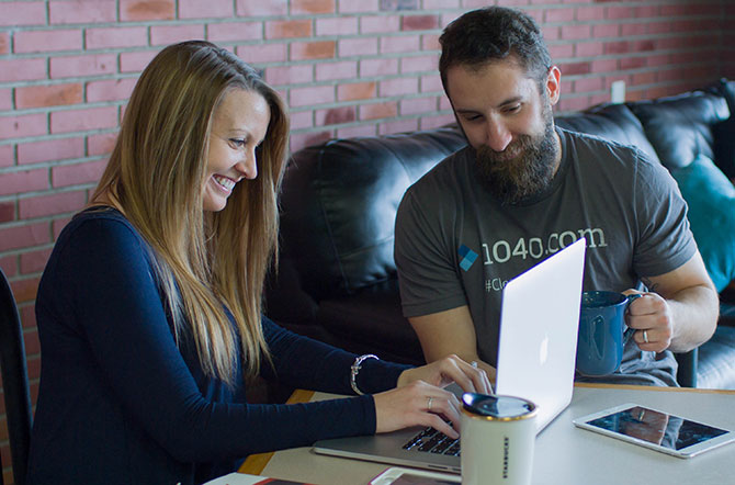 A 1040.com employee helps a young woman with online finances on her laptop.