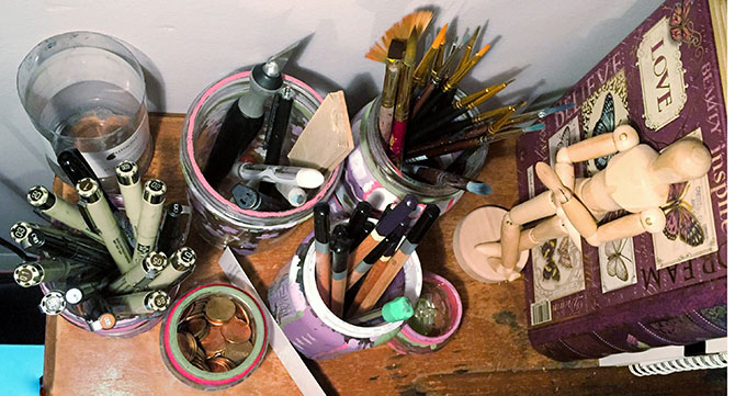 Pens, pencils and paintbrushes next to a drawing mannequin