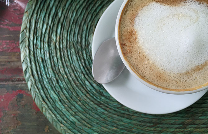 A latte  on a green woven placemat.