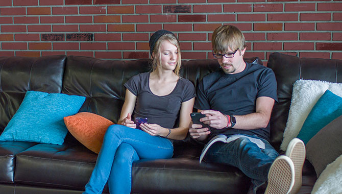 A couple sitting on a couch to use a laptop.