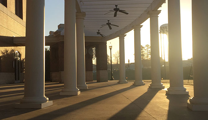 Sunrise light beams shining through a pillared walkway