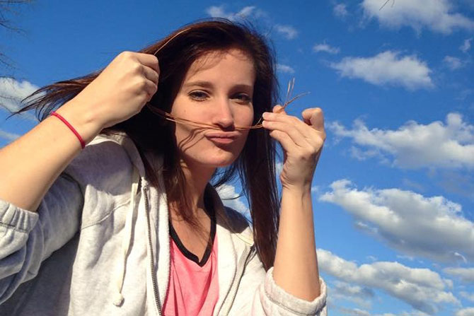 A college student posing with a pine straw moustache