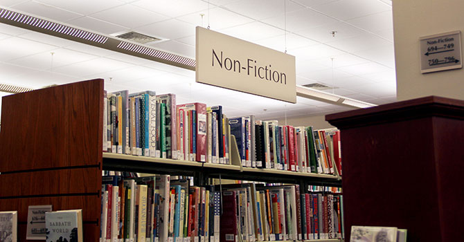 A large sign saying non-fiction hanging over a bookshelf in a public library