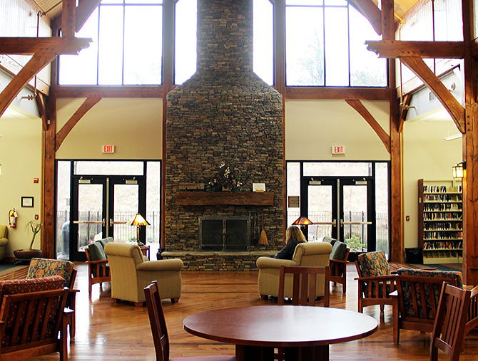 The lobby of a public library, with a fireplace and several tables, chairs, and couches