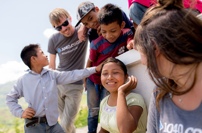 Two 1040.com employees laughing with Guatemalan children at an overlook.