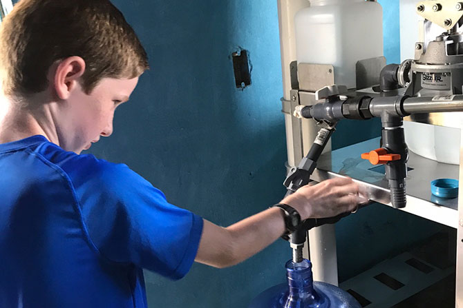 James Stork’s son helps fill a five gallon jug at a clean water site.