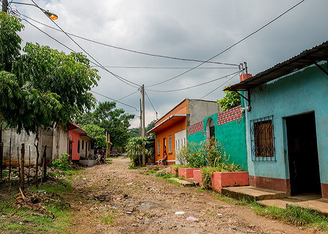 Brightly colored buildings line a dirt and cobblestone street in Portales, Guatemala.
